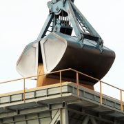 Garra mecânica descarrega carga a granel em um terminal portuário industrial.