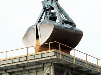 Garra mecânica descarrega carga a granel em um terminal portuário industrial.