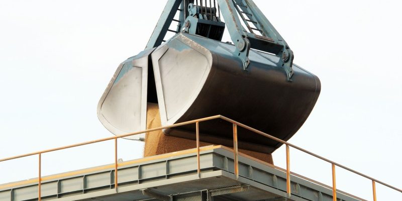 Garra mecânica descarrega carga a granel em um terminal portuário industrial.