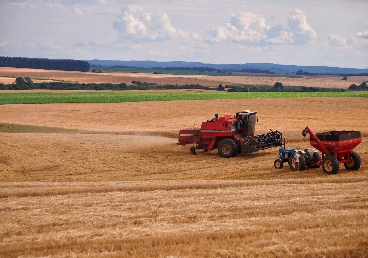 Colheitadeira e trator trabalhando em lavoura durante a colheita em Entre Rios, Brasil.