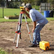 Profissional realiza medições com equipamento topográfico em uma área rural.